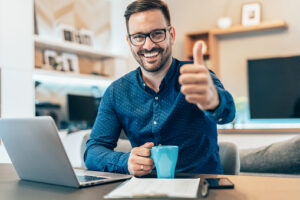 Man with a coffee working on a laptop